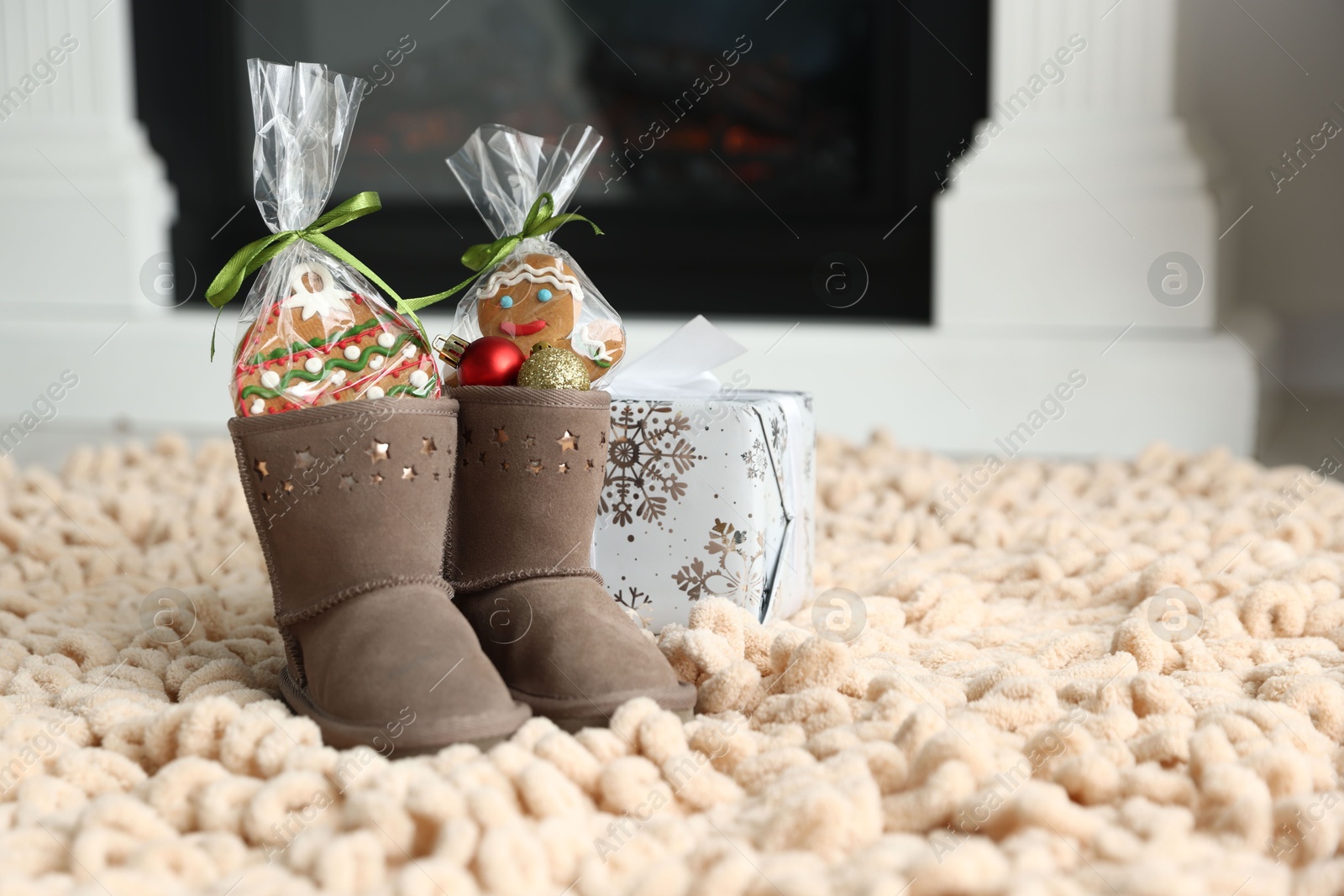 Photo of Saint Nicholas day tradition. Boots with sweets, baubles and gift box on floor indoors, space for text