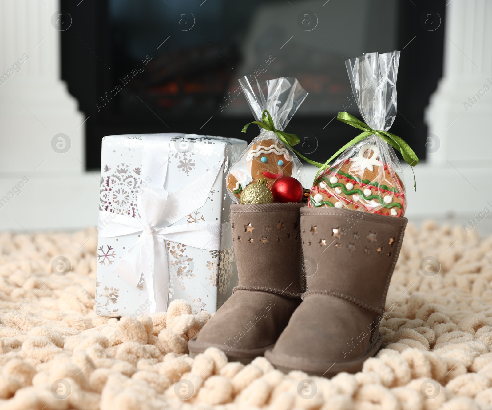 Photo of Saint Nicholas day tradition. Boots with sweets, baubles and gift box on floor indoors