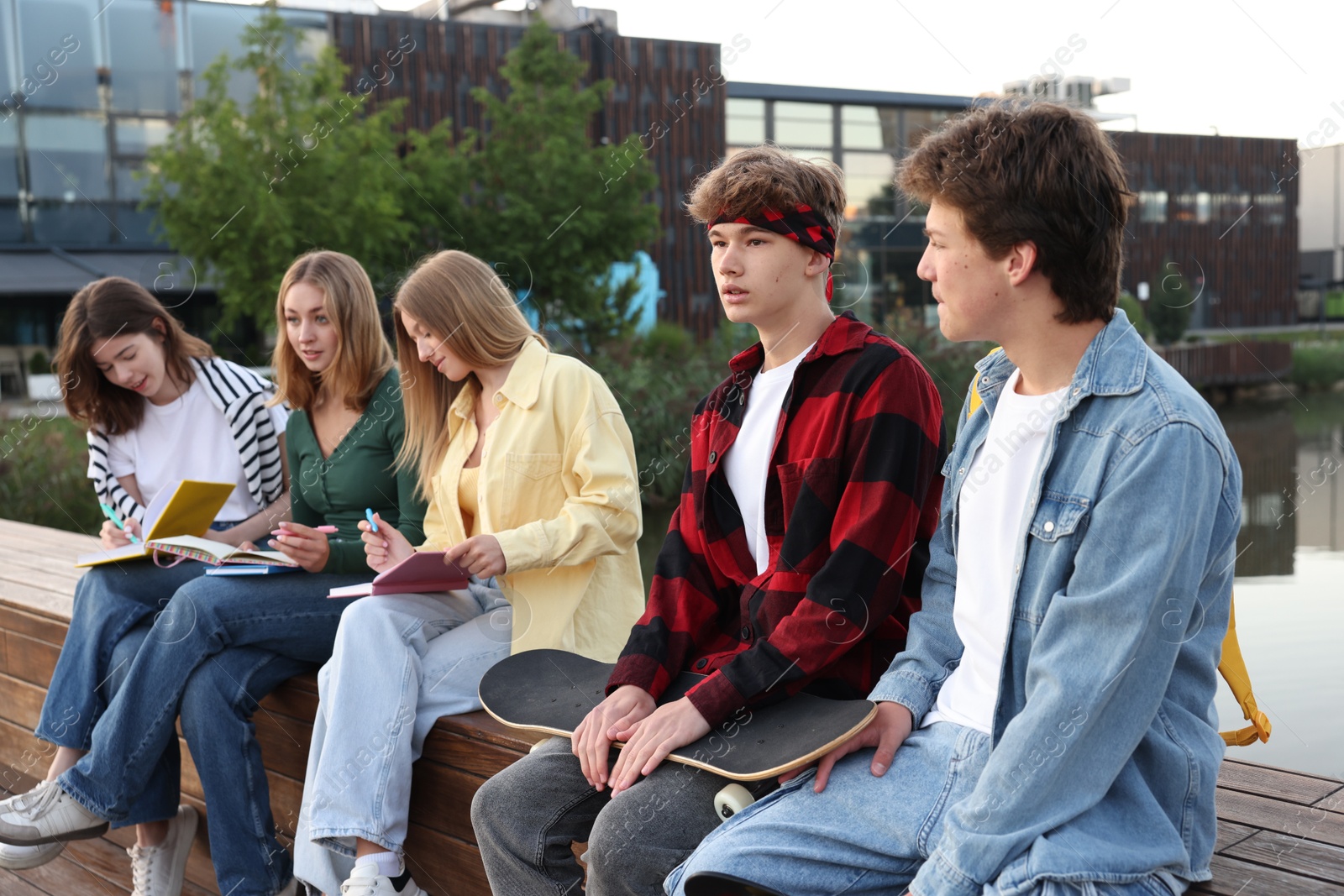 Photo of Group of teenagers spending time together near lake outdoors