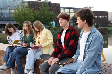 Photo of Group of teenagers spending time together near lake outdoors