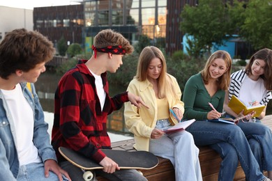 Photo of Group of teenagers doing homework together outdoors