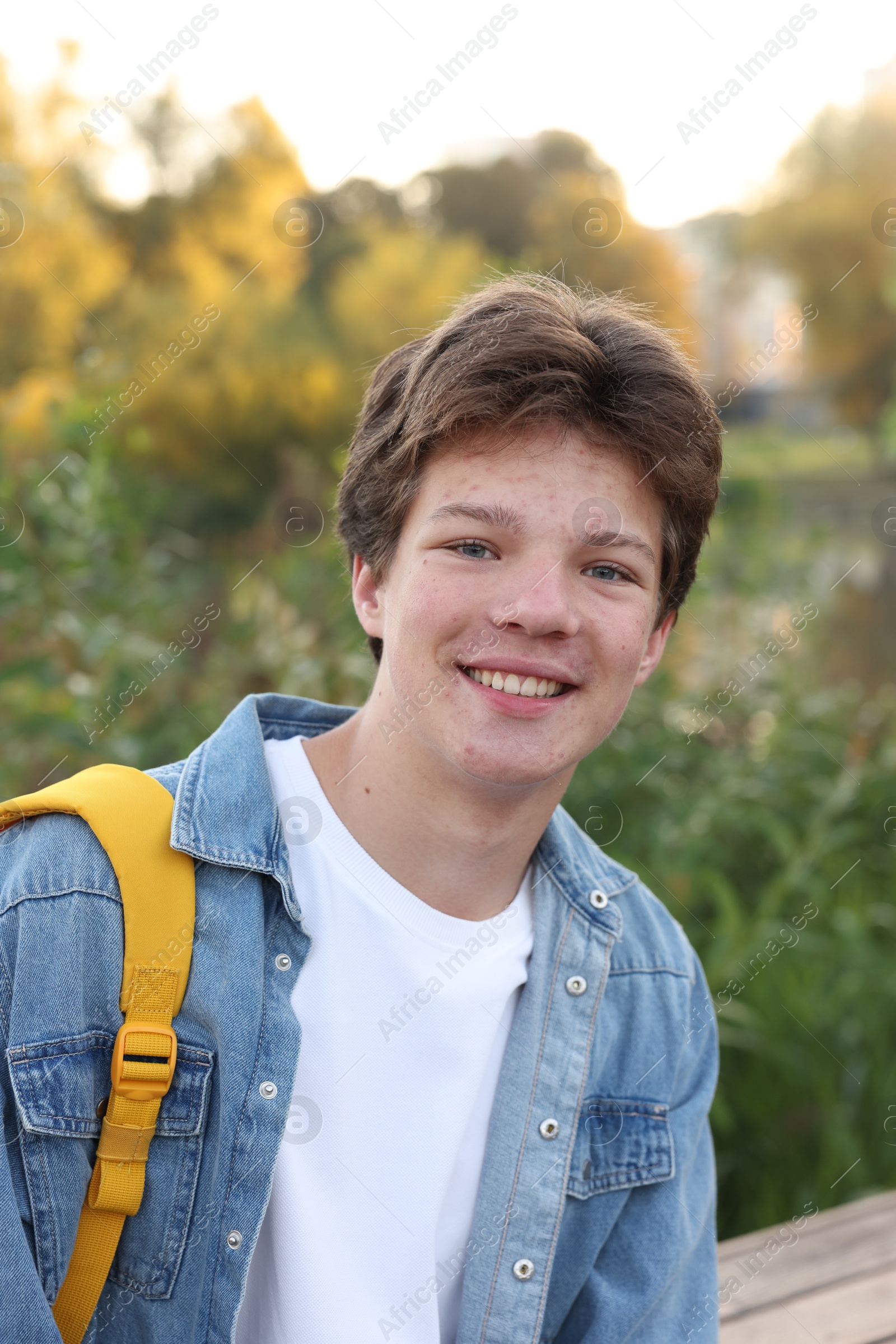 Photo of Portrait of happy teenage boy with backpack outdoors