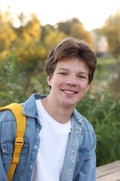 Photo of Portrait of happy teenage boy with backpack outdoors