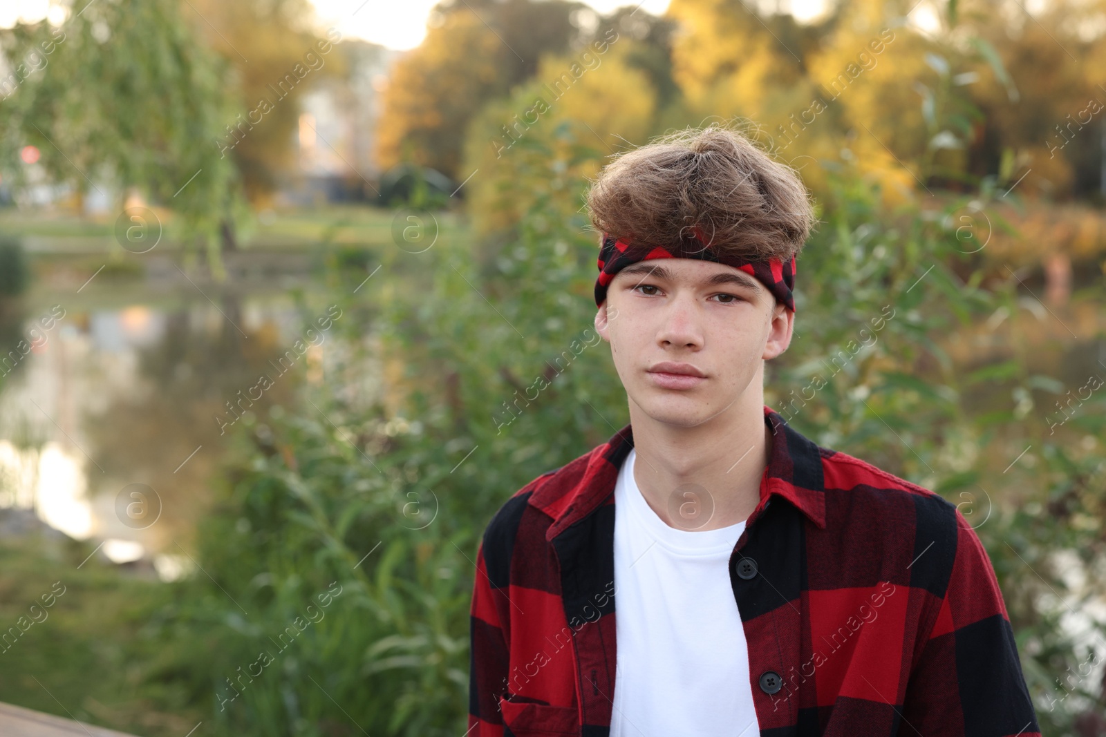 Photo of Portrait of teenage boy near lake outdoors, space for text