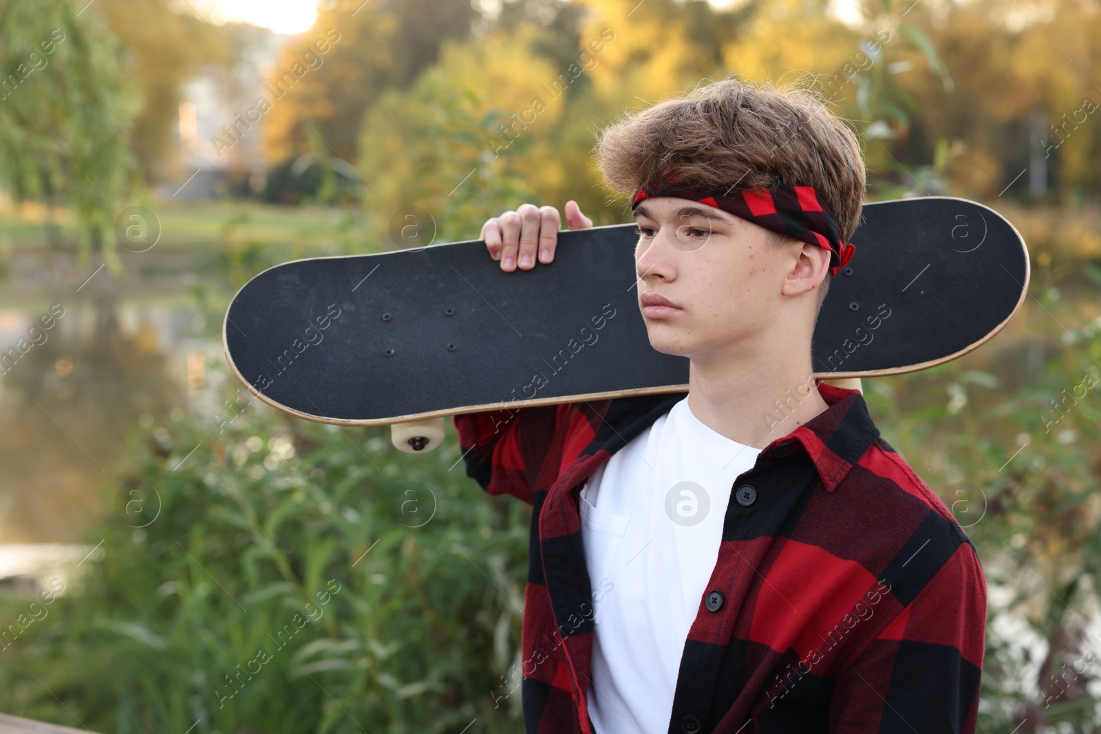 Photo of Teenage boy with skateboard near lake outdoors