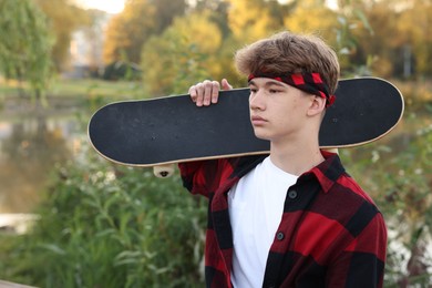 Photo of Teenage boy with skateboard near lake outdoors
