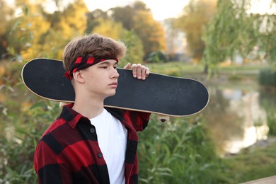 Photo of Teenage boy with skateboard near lake outdoors