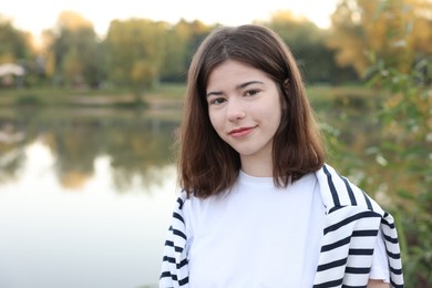 Photo of Teenage girl near lake outdoors, space for text
