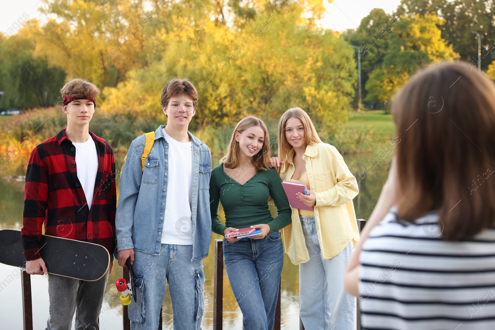 Photo of Teenage girl taking photo of her friends near lake outdoors
