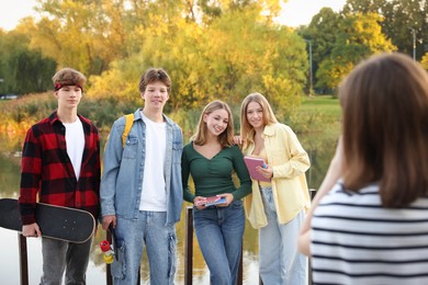 Photo of Teenage girl taking photo of her friends near lake outdoors