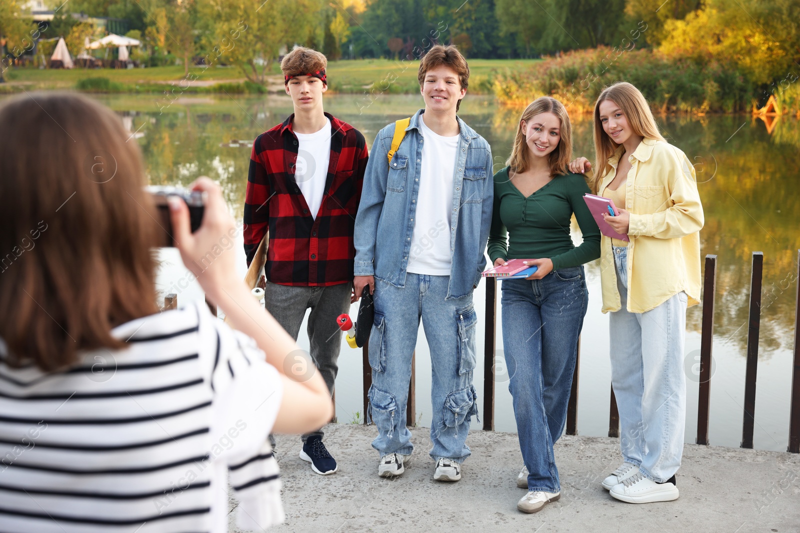 Photo of Teenage girl taking photo of her friends near lake outdoors