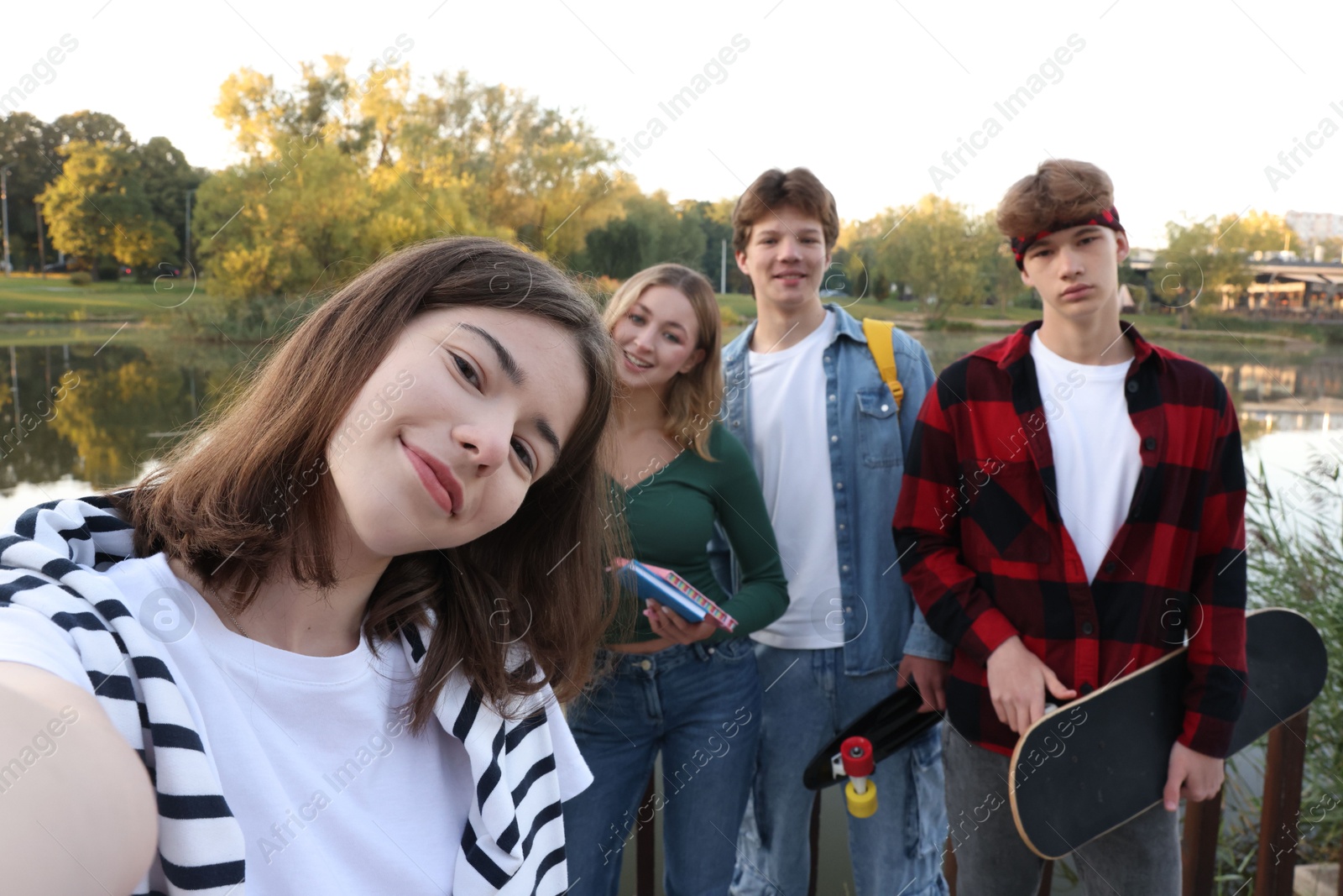 Photo of Group of teenagers taking selfie near lake outdoors