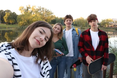 Photo of Group of teenagers taking selfie near lake outdoors