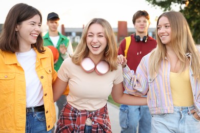 Photo of Group of teenagers walking on city street, selective focus