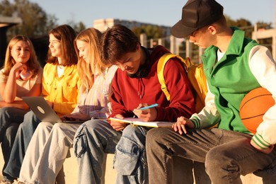 Photo of Group of teenagers doing homework together outdoors