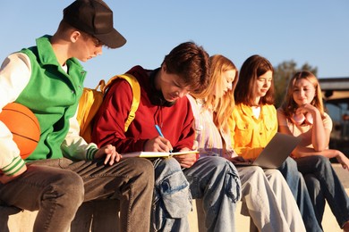 Photo of Group of teenagers doing homework together outdoors