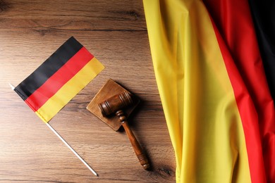 Photo of Judge's gavel and flags of Germany on wooden table, top view