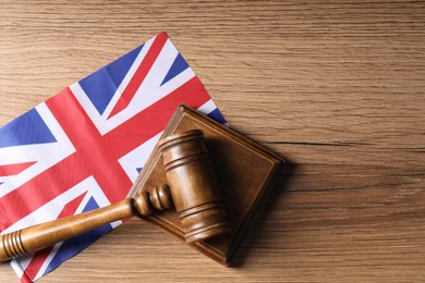 Photo of Judge's gavel and flag of United Kingdom on wooden table, top view. Space for text
