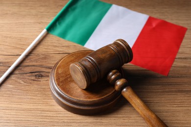 Photo of Judge's gavel and flag of Italy on wooden table, closeup