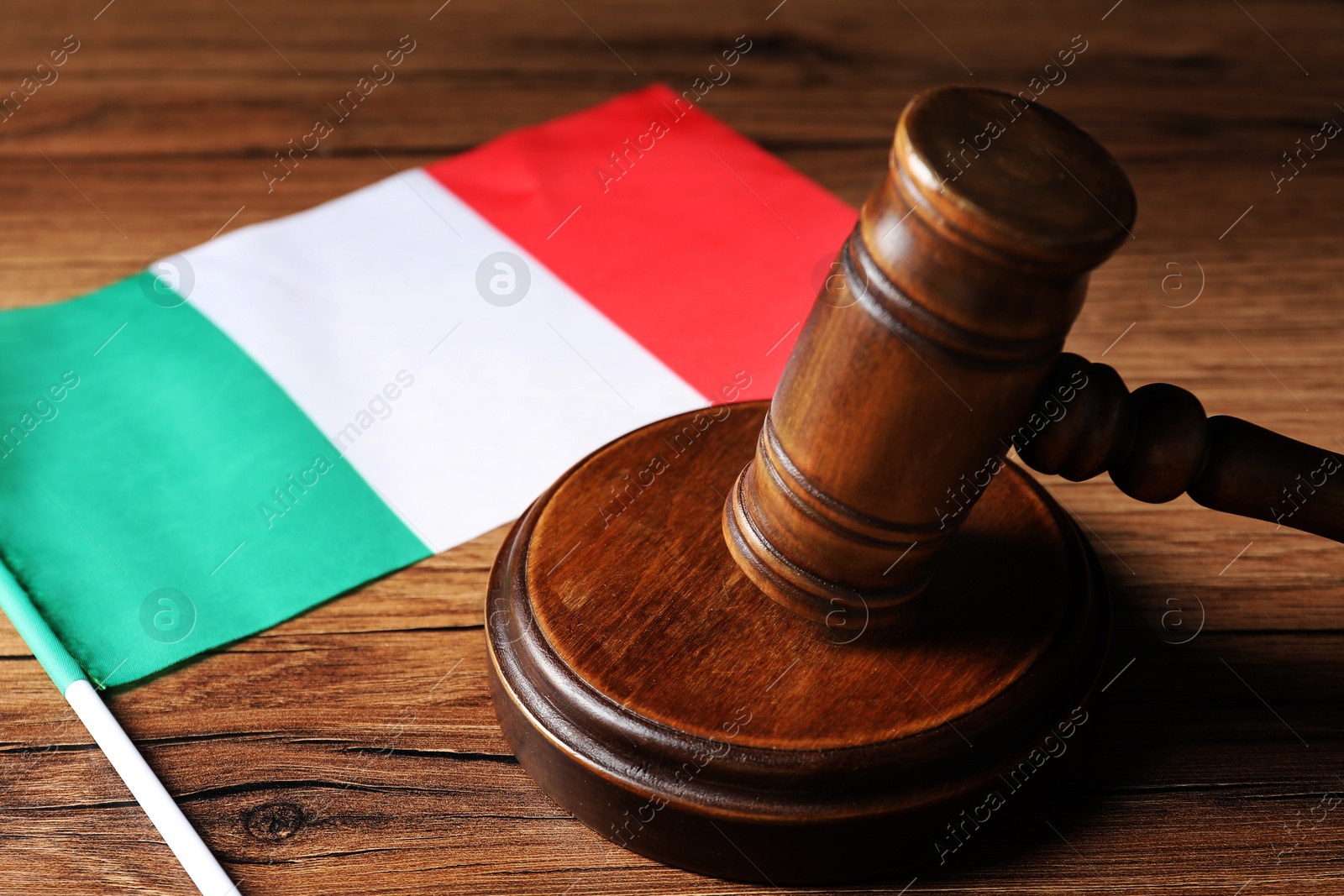 Photo of Judge's gavel and flag of Italy on wooden table, closeup