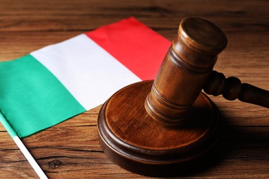 Photo of Judge's gavel and flag of Italy on wooden table, closeup