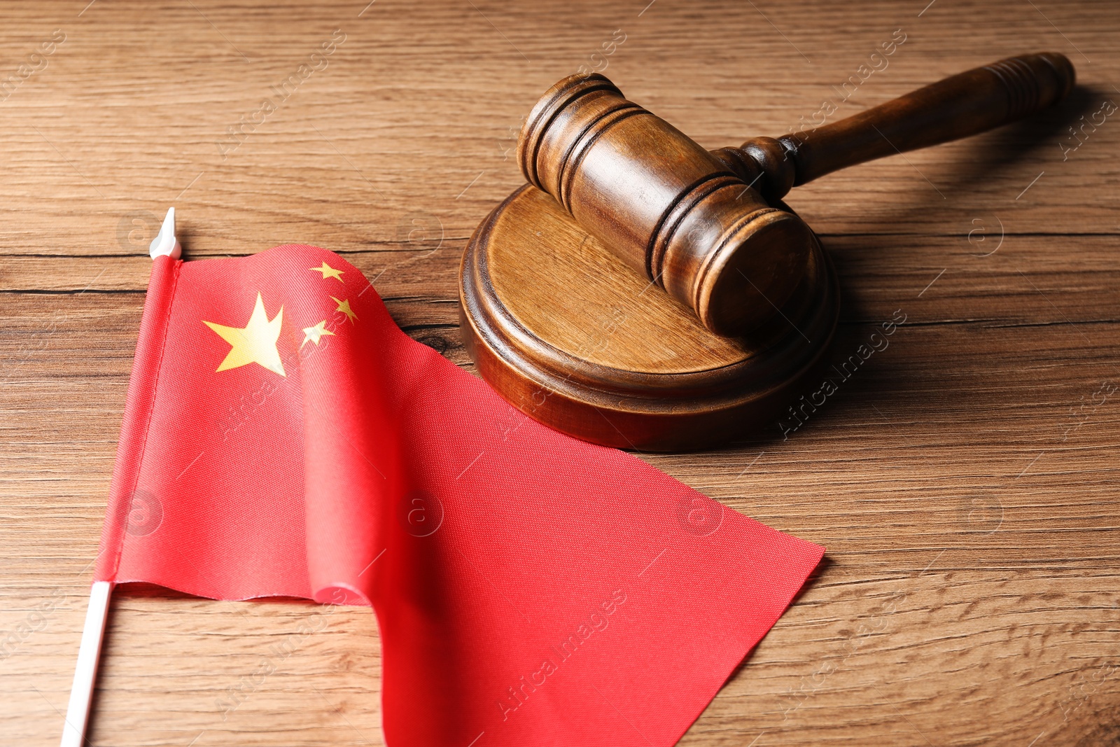 Photo of Judge's gavel and flag of China on wooden table
