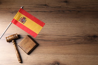 Photo of Judge's gavel and flag of Spain on wooden table, top view. Space for text