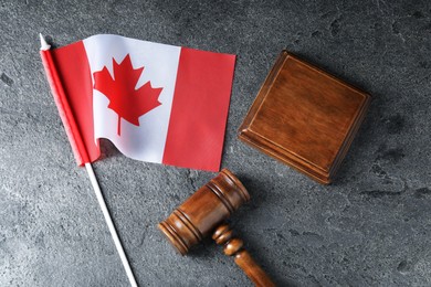 Photo of Judge's gavel and flag of Canada on grey table, top view