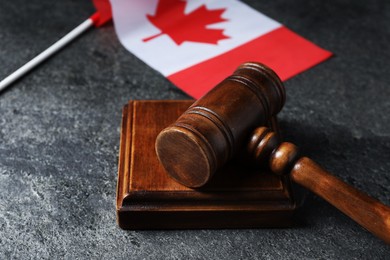 Photo of Judge's gavel and flag of Canada on grey table, closeup