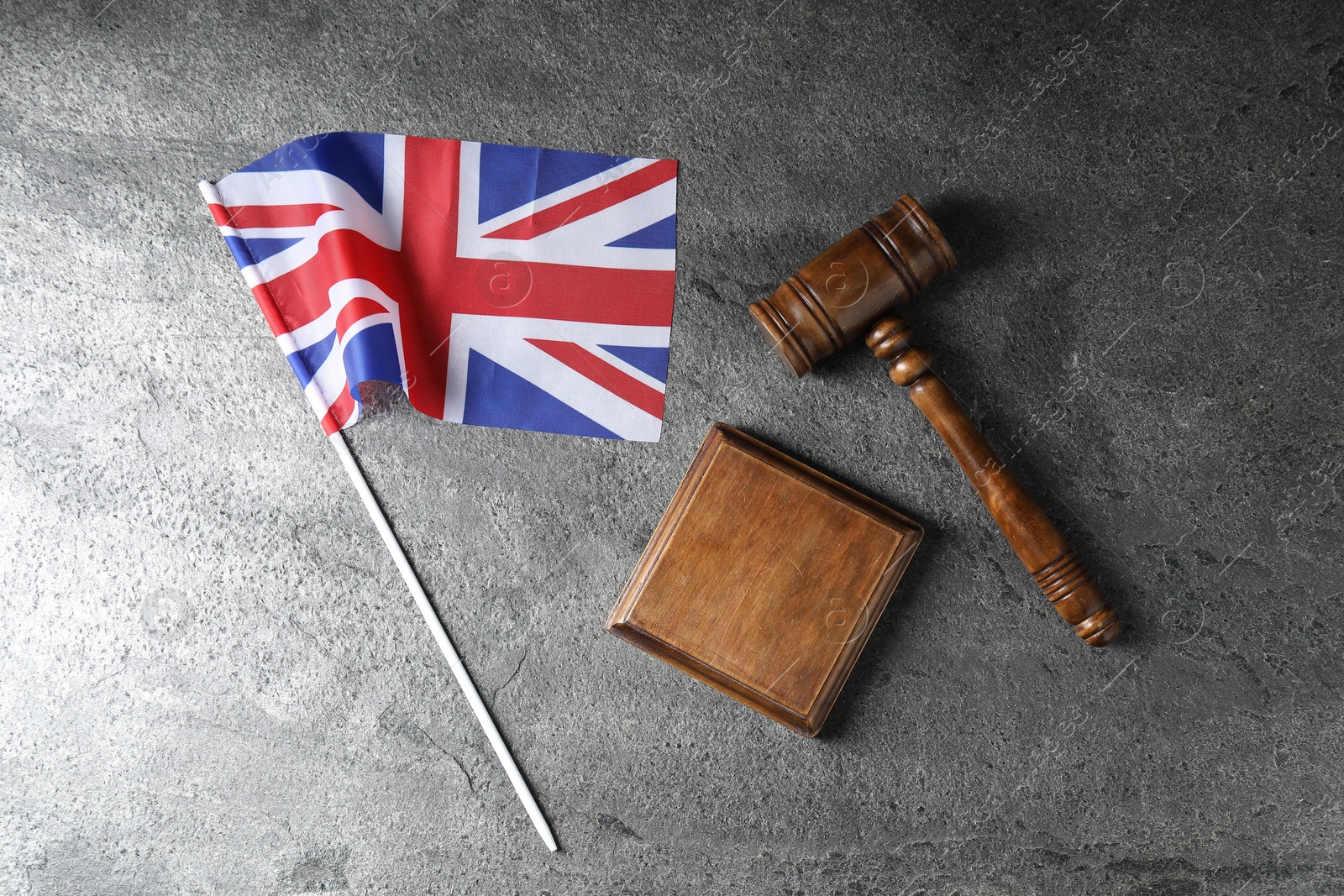Photo of Judge's gavel and flag of United Kingdom on wooden table, top view