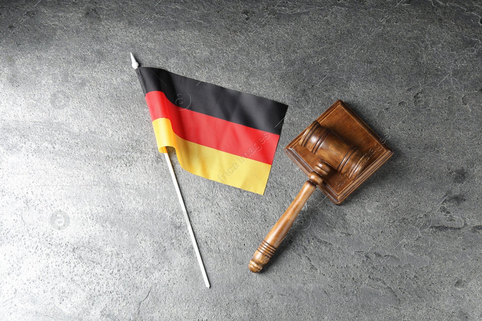 Photo of Judge's gavel and flag of Germany on wooden table, top view