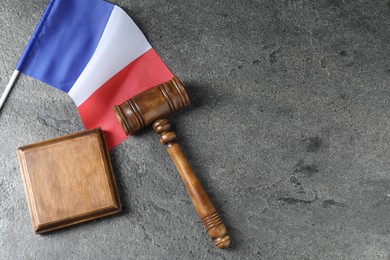Photo of Judge's gavel and flag of France on grey table, top view. Space for text