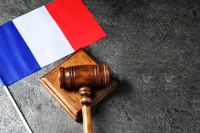 Photo of Judge's gavel and flag of France on grey table, top view. Space for text