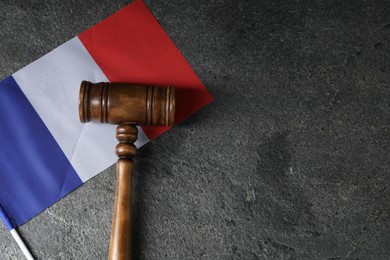 Photo of Judge's gavel and flag of France on grey table, top view. Space for text