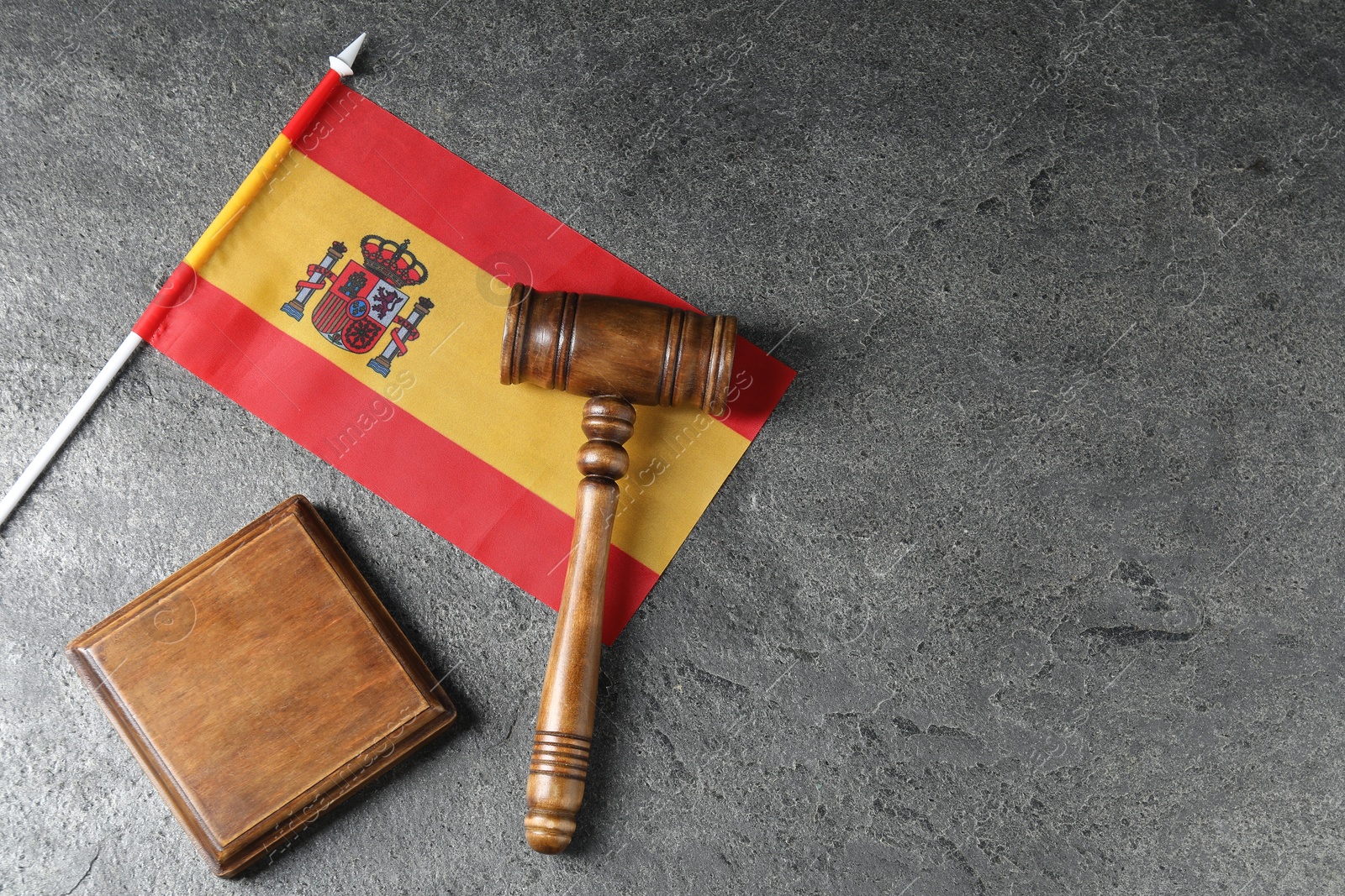 Photo of Judge's gavel and flag of Spain on grey table, top view. Space for text