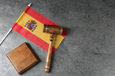 Photo of Judge's gavel and flag of Spain on grey table, top view. Space for text