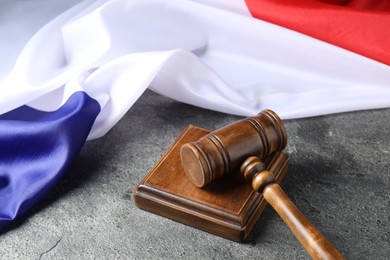 Photo of Judge's gavel and flag of France on grey table, closeup
