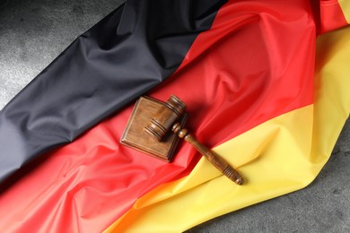 Photo of Judge's gavel and flag of Germany on grey table, top view