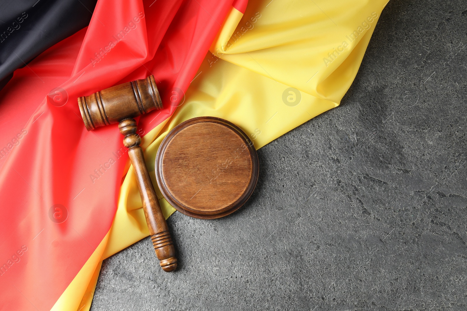 Photo of Judge's gavel and flag of Germany on grey table, top view. Space for text