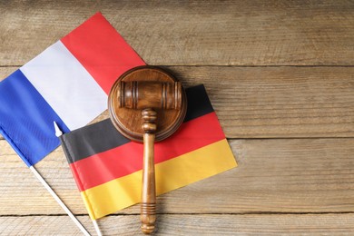 Photo of Judge's gavel and flags of Germany and France on wooden table, top view. Space for text