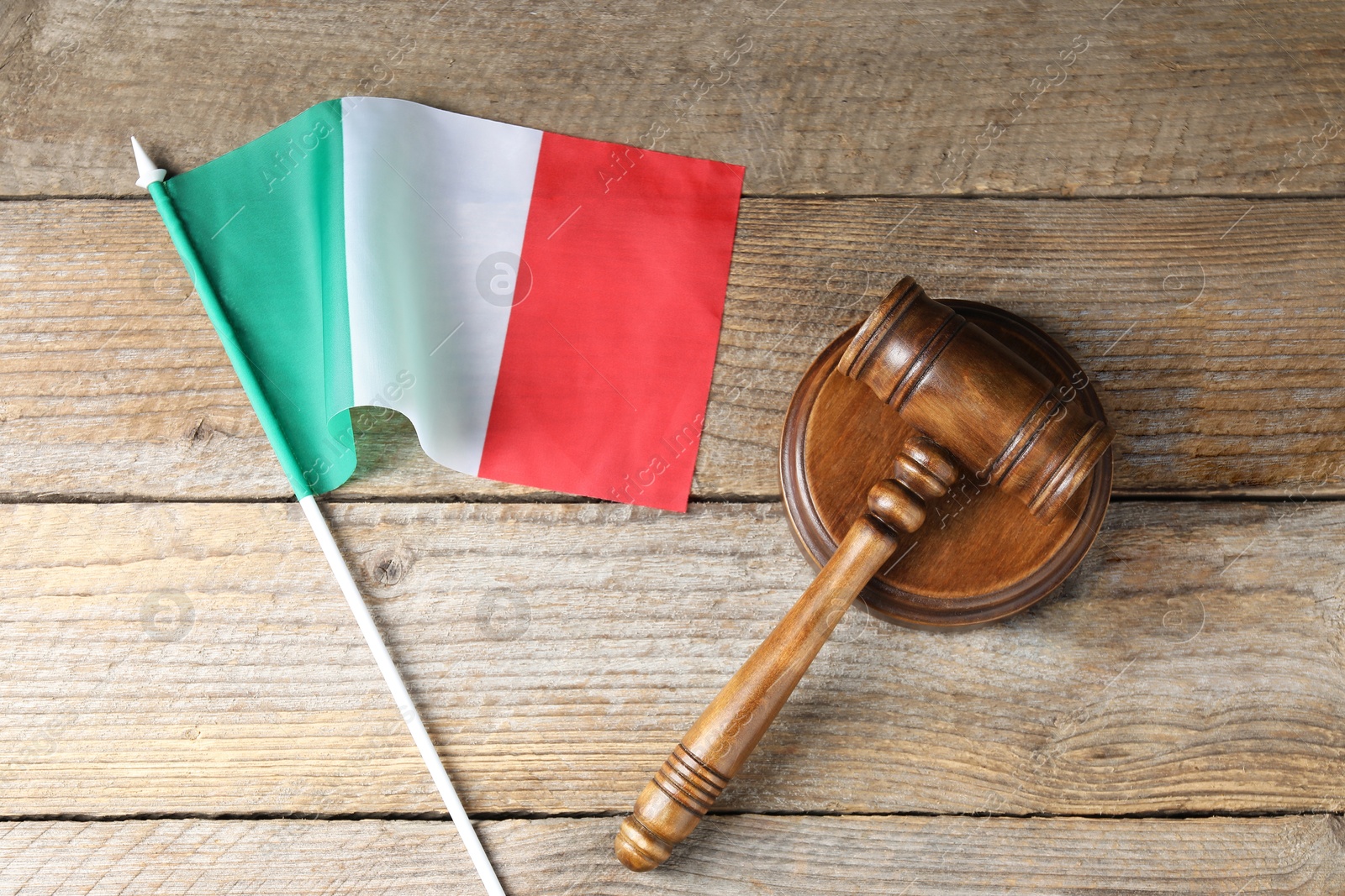Photo of Judge's gavel and flag of Italy on wooden table, top view
