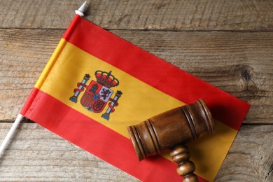 Photo of Judge's gavel and flag of Spain on wooden table, top view