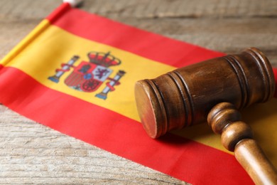 Photo of Judge's gavel and flag of Spain on wooden table, closeup