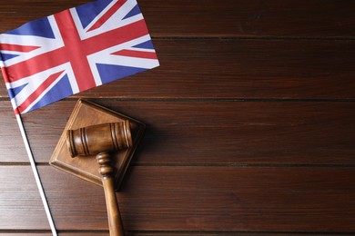 Photo of Judge's gavel and flag of United Kingdom on wooden table, top view. Space for text