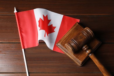 Photo of Judge's gavel and flag of Canada on wooden table, top view