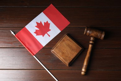 Photo of Judge's gavel and flag of Canada on wooden table, top view