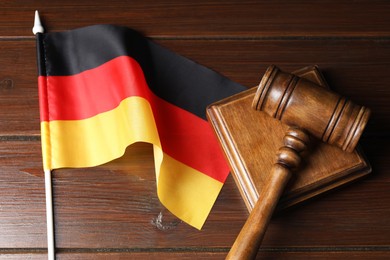 Photo of Judge's gavel and flag of Germany on wooden table, top view