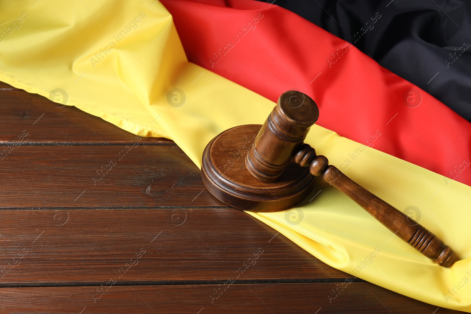 Photo of Judge's gavel and flag of Germany on wooden table. Space for text