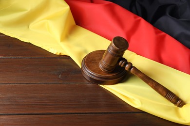 Photo of Judge's gavel and flag of Germany on wooden table. Space for text