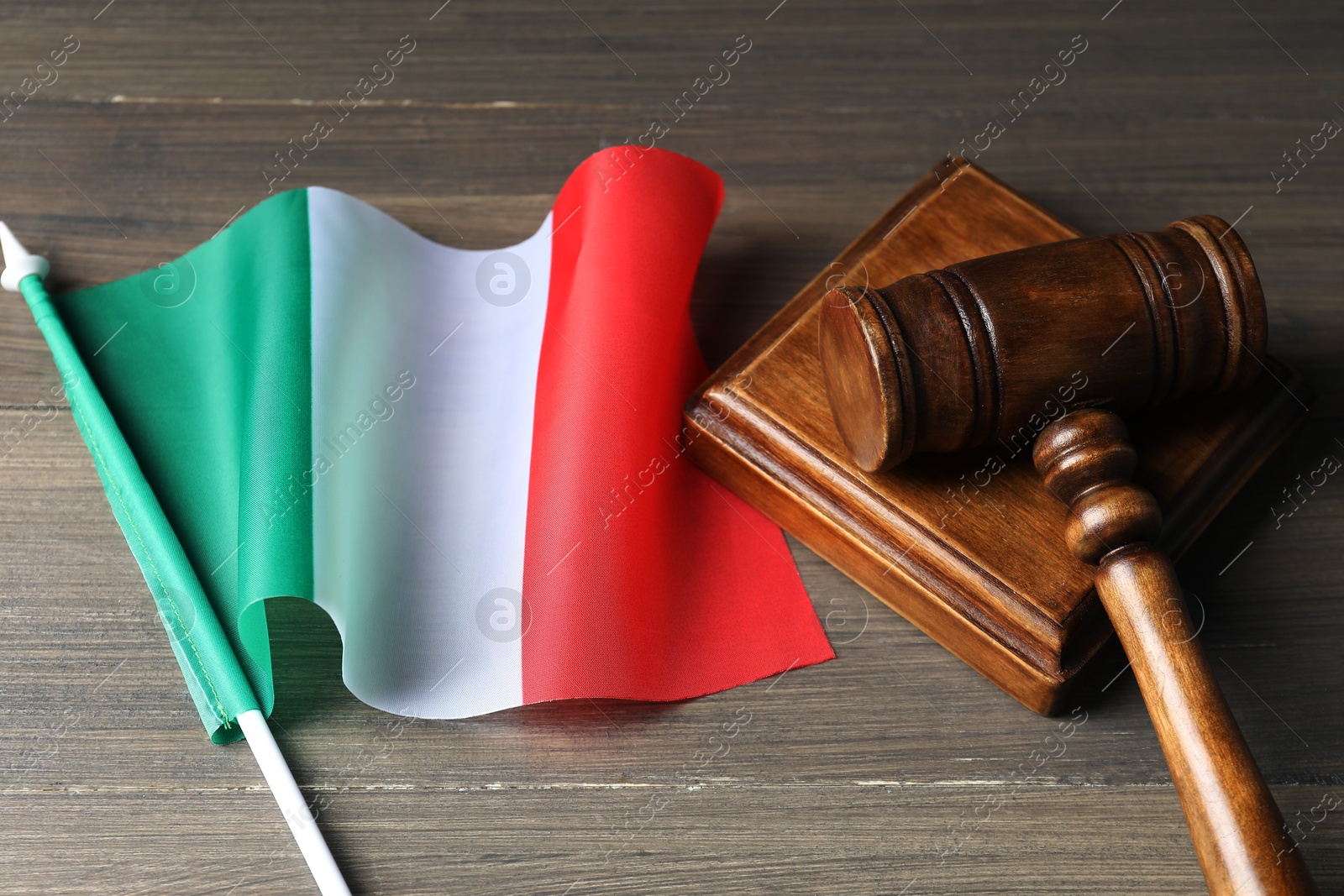 Photo of Judge's gavel and flag of Italy on wooden table, closeup